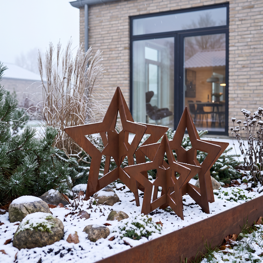 Rostbraune Deko-Sterne aus Cortenstahl in verschiedenen Größen im winterlichen Gartenbeet mit Einfassung aus Cortenstahl.